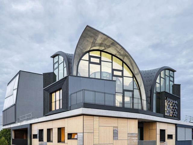 A building corner topped by a curved, glazed concrete shell roof unit